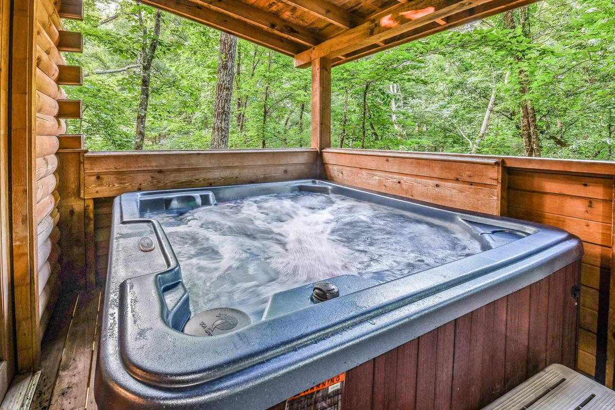 A serene indoor hot tub nestled within a wooden structure, surrounded by lush greenery. The atmosphere is tranquil, inviting guests to relax and soak while enjoying the natural views.
